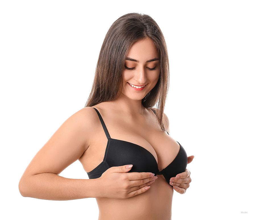 woman wearing a black bra with both hands lifting her breasts up
