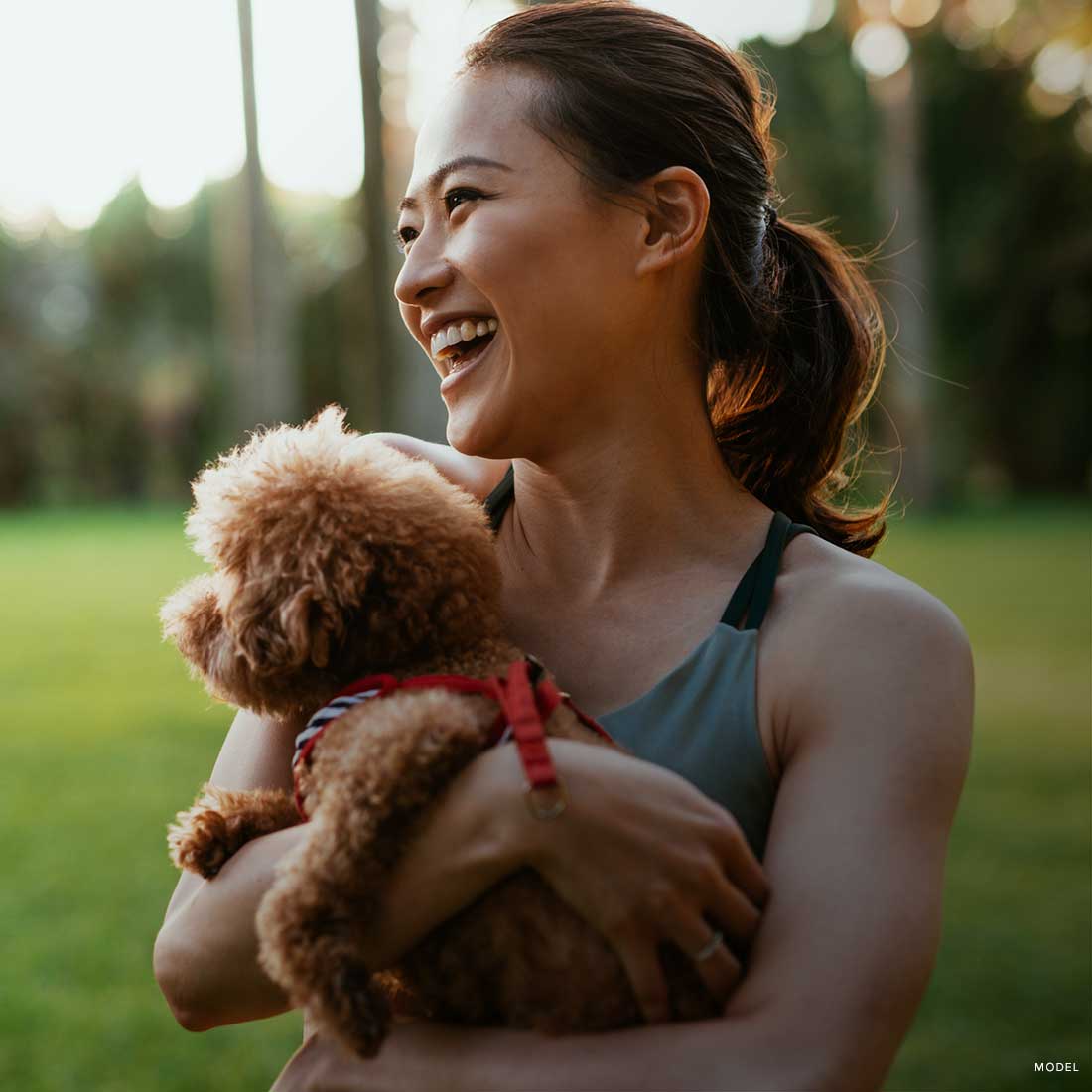 Asian woman with happily holding a dog in a park