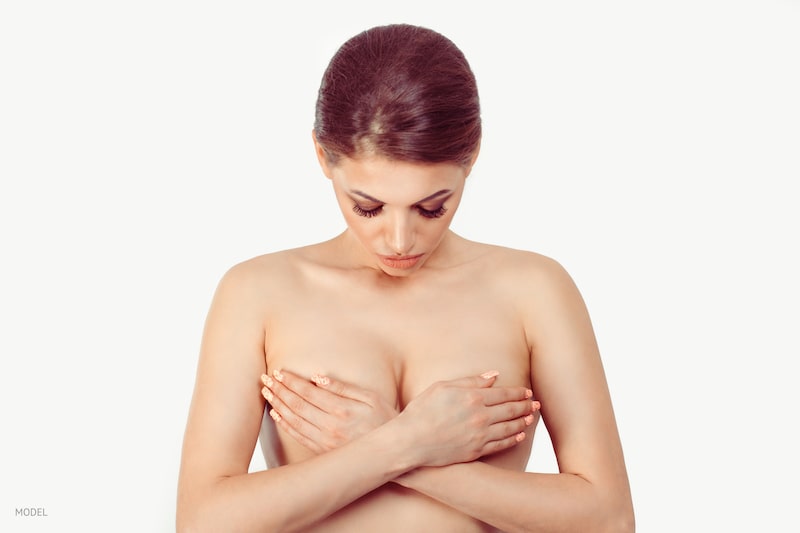 Woman crossing her arms over her bare breasts