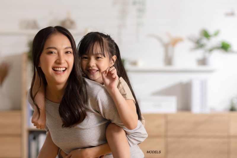 Mother carrying her daughter on her back.