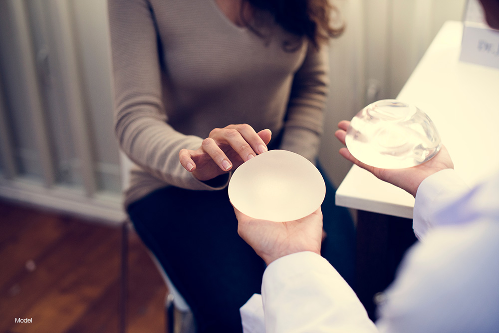 woman being shown two different types of breast implants