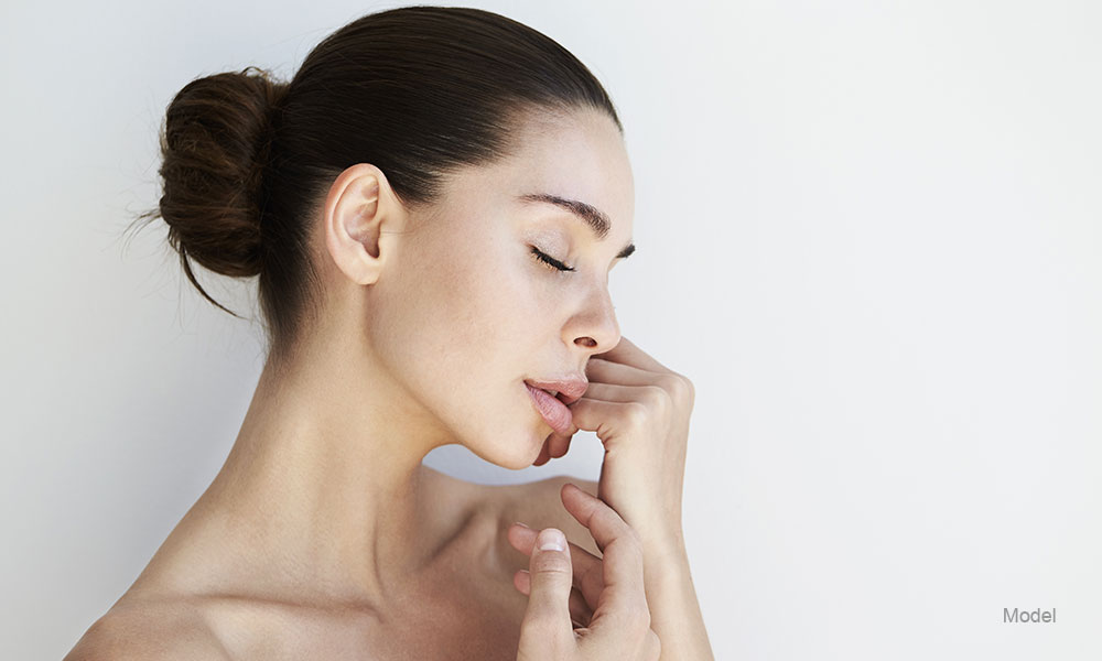 woman with her eye closed touching her face