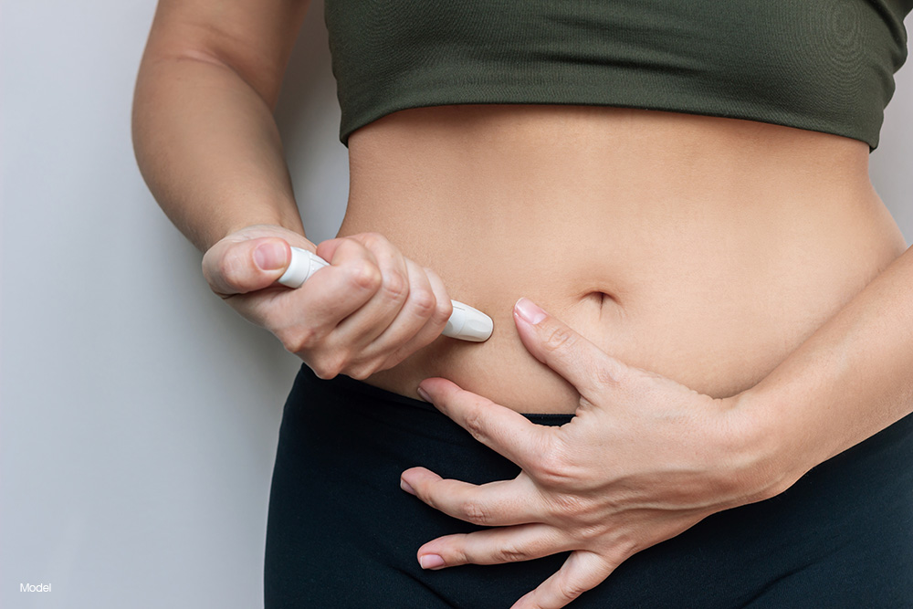 A woman giving herself an injection in her stomach